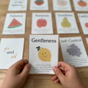 May include: A rectangular card featuring the word Gentleness in black text above a yellow lemon illustration with a smiling face. Below the lemon, the text reads: A gentle answer will calm a person's anger. But an unkind answer will cause more anger. Proverbs 15:1, ICB.