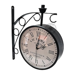 May include: Black metal double-sided clock with Roman numerals and the text "Victoria Station Railway Clock London".
