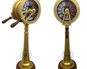 May include: A brass ship's wheel telegraph with a wooden base. The wheel has a black face with red markings and the text "Engine Room Telegraph" and "Full Ahead" on it. The wheel is mounted on a tall, slender brass stand with a wooden base.