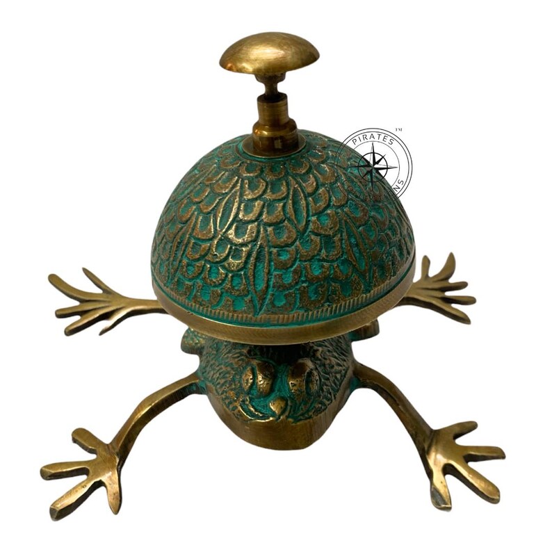 May include: A brass frog-shaped door bell with a green and gold dome. The dome has a decorative pattern and the frog has outstretched legs.