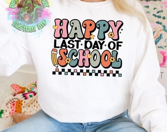 May include: White sweatshirt with a colourful graphic that says "Happy Last Day of School" in a retro font. The graphic includes a pencil, flowers, and stars.
