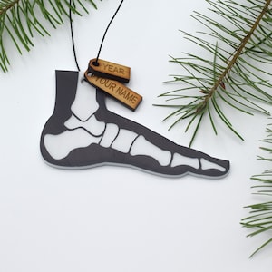 May include: A black and white foot bone ornament with a wooden tag that says "YEAR" and another wooden tag that says "YOUR NAME".