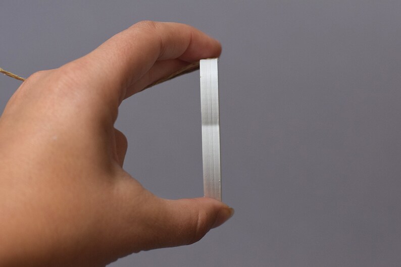 May include: A white, rectangular, adhesive tape dispenser with a brown string attached to it.