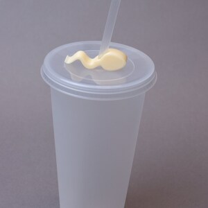 Puede incluir: Un vaso de pl&aacute;stico transparente con tapa y una pajita. La pajita est&aacute; doblada y pegada a la tapa.
