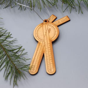 Puede incluir: Adorno de Navidad de madera con forma de transportador con las palabras "YEAR" y "YOUR NAME" en él.