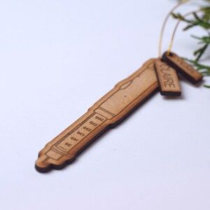 May include: A wooden ornament shaped like a syringe with a tag that reads "CLAIRE".