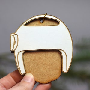Pu&ograve; includere: Addobbo natalizio in legno bianco a forma di casco con un ritaglio per il viso in legno marrone.