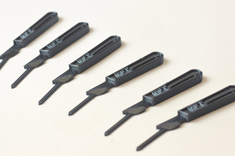 May include: Six black plastic scalpel-shaped tools with a raised inscription that reads "MIFE" on each tool.