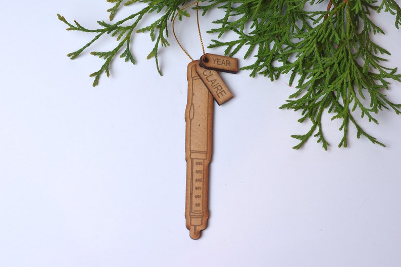 May include: A wooden ornament shaped like a pen with a tag that says "Claire" and another tag that says "Year".