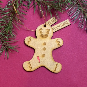 May include: A wooden gingerbread man ornament with a red icing detail. The ornament has a tag that says "YEAR" and "YOUR NAME".