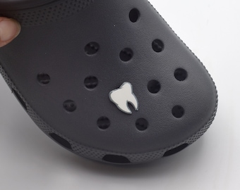 May include: A dark gray clog with a white tooth charm attached to the top.
