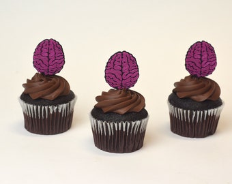 May include: Three chocolate cupcakes topped with pink brain-shaped decorations.