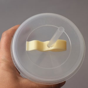 Puede incluir: Un vaso de pl&aacute;stico transparente con tapa y una pajita. La tapa tiene una leng&uuml;eta de pl&aacute;stico amarilla que se utiliza para sujetar la pajita en su lugar.