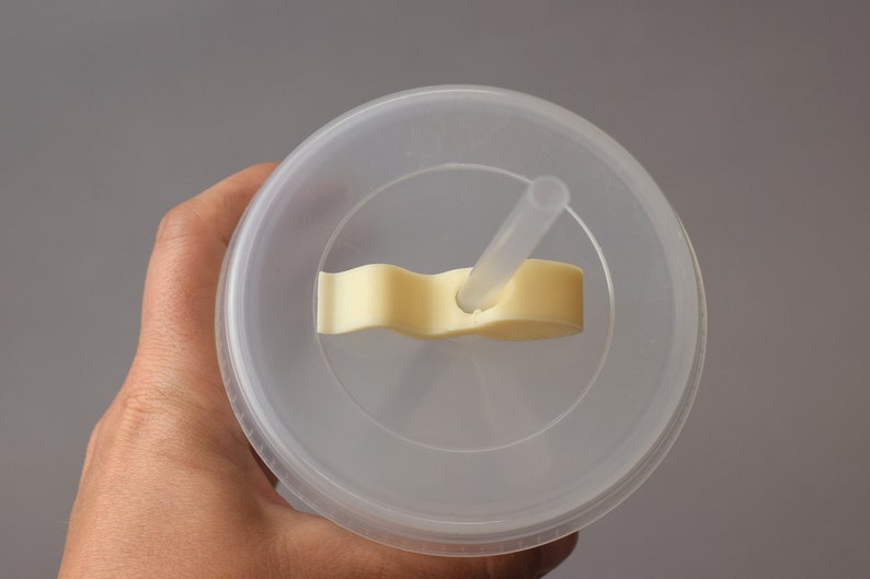 Puede incluir: Un vaso de pl&aacute;stico transparente con tapa y una pajita. La tapa tiene una leng&uuml;eta de pl&aacute;stico amarilla que se utiliza para sujetar la pajita en su lugar.