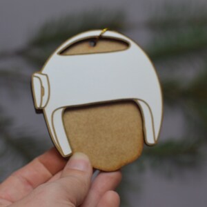 Pu&ograve; includere: Ciondolo in legno bianco a forma di casco con un ritaglio per il viso in legno marrone.
