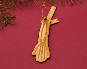 May include: Wooden skeleton arm ornament with a tag for writing "Your Name" and "Year".