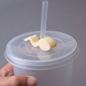 Puede incluir: Un vaso de pl&aacute;stico transparente con tapa y una pajita. La tapa tiene un soporte de pajita de pl&aacute;stico blanco con forma de nota musical.