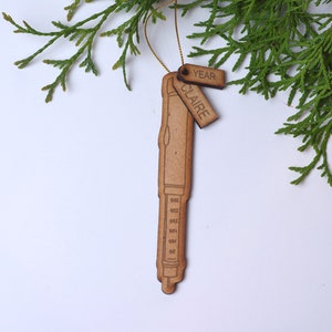 May include: A wooden ornament shaped like a pen with a tag that says "Claire" and another tag that says "Year".