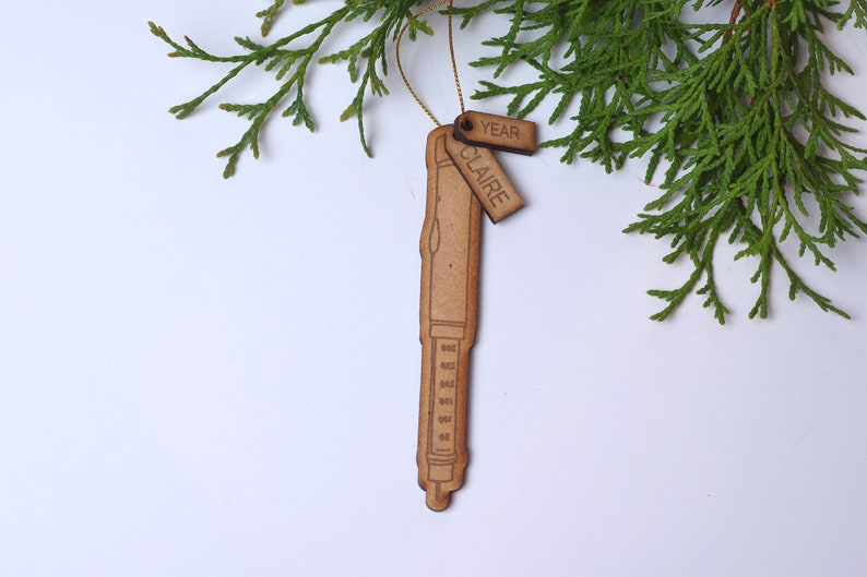 May include: A wooden ornament shaped like a pen with a tag that says "Claire" and another tag that says "Year".