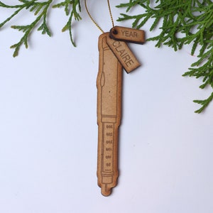 May include: Wooden ornament shaped like a pen with a tag that says "Claire" and another tag that says "Year".