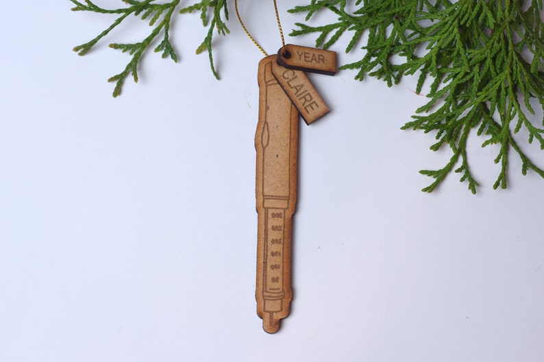 May include: Wooden ornament shaped like a pen with a tag that says "Claire" and another tag that says "Year".