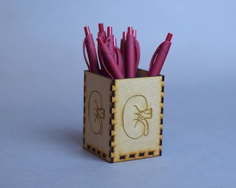 May include: A wooden pencil holder with a kidney design. The holder is filled with red pens.