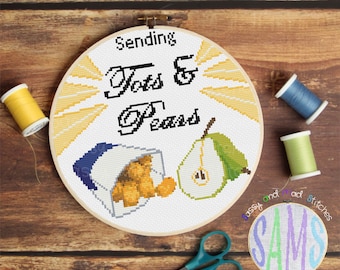Op de afbeelding: Een witte borduurring met een kruissteekontwerp van een zak met tots en een peer. De tekst "Sending Tots & Pears" is in zwart garen geborduurd boven het ontwerp. De ring ligt op een houten oppervlak met een schaar en garenrollen.