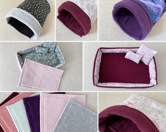 Peut inclure: Un ensemble de six lits pour animaux de compagnie de différentes couleurs et motifs. Les lits comprennent un lit rectangulaire doublé de polaire bordeaux, un tunnel doublé de polaire bordeaux, un lit rectangulaire doublé de polaire bordeaux avec un imprimé floral et trois coussins rectangulaires doublés de polaire en rose, vert et gris.