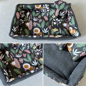 Peut inclure: Un petit lit pour animaux de compagnie avec un oreiller assorti. Le lit a un extérieur en polaire gris foncé et un intérieur à motifs avec des lions, des singes et du feuillage tropical en vert, rose et jaune. L'oreiller est rectangulaire.