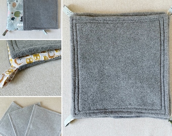 Peut inclure: Des dessous de plat carrés gris avec un extérieur en polaire et un intérieur à motifs. Les dessous de plat ont de petites boucles aux coins pour les suspendre. L'un a un motif de forêt, et l'autre un motif de hibou.