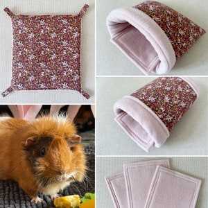 Puede incluir: Un conjunto de cuatro camas para conejillos de indias con estampado floral rosa. La ropa de cama est&aacute; hecha de suave vell&oacute;n e incluye una cama plana, un t&uacute;nel y dos piezas planas. Se muestra un conejillo de indias en la imagen.