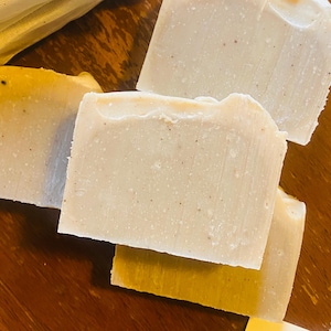 May include: Three bars of handmade soap, two are white with flecks of color and one is yellow.
