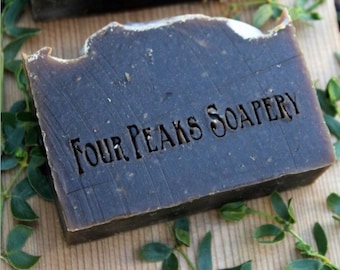 May include: Two dark brown bars of soap with the text "Four Peaks Soapery" stamped on the top bar.