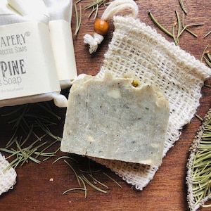 May include: A gray bar of soap with a white mesh bag. The soap is labeled "APERY® PROCESS SOAPS PINE Soap of the Southwest".