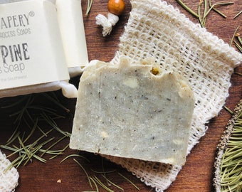 Op de afbeelding: Een grijze zeep in blok met een witte gaas zak. De zeep is gelabeld met "APERY® PROCESS SOAPS PINE Soap of the Southwest".