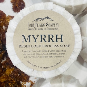 May include: Round bar of Myrrh Resin Cold Process Soap from Four Peaks Soapery. The soap is wrapped in white paper and has a tan label with black text. The label lists ingredients and net weight of 4-5 oz.