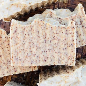 May include: Close-up of a bar of handmade soap with a speckled brown and white appearance. The soap is made with natural ingredients and is ideal for sensitive skin.