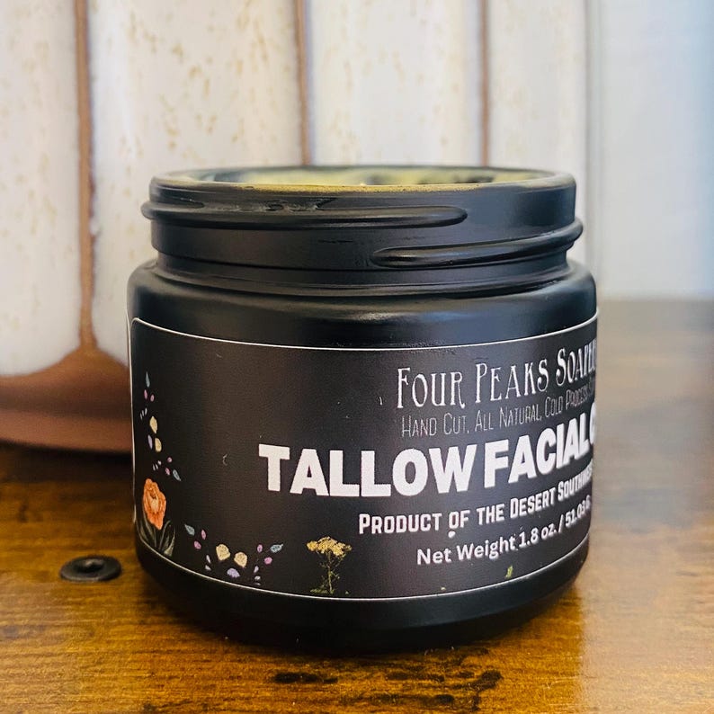 May include: A black jar of Tallow Facial cream with a black lid. The label reads "Four Peaks Soap" and "Product of the Desert Southwest." The net weight is 1.8 oz. Floral illustrations decorate the label.
