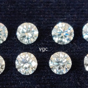 Könnte beinhalten: Acht runde, klare, facettierte Edelsteine auf einem schwarzen Stoffhintergrund. Die Edelsteine sind in zwei Reihen zu je vier angeordnet. Der Text "vgc" ist in der Mitte des Bildes gedruckt.