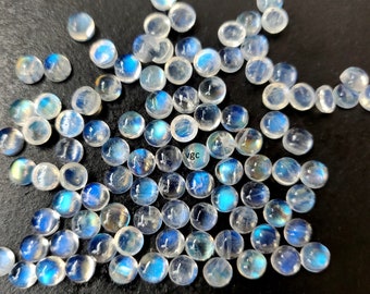 May include: A collection of round, iridescent moonstone cabochons in various sizes. The stones are a milky white color with a blue sheen.