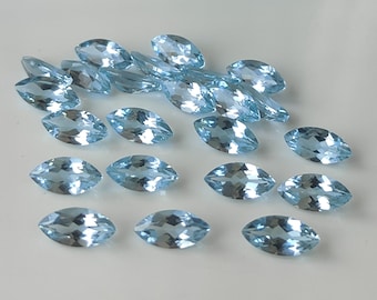 May include: A collection of light blue marquise cut gemstones. The gemstones are faceted and have a brilliant shine.
