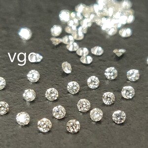 May include: A collection of small, round, clear diamonds on a black surface. The diamonds are scattered around the surface, with some clustered together. The text "vgc" is visible in the upper left corner of the image.