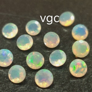May include: A collection of 14 white opal gemstones, each with a slightly different iridescent sheen. The stones are round and have a smooth, polished finish.