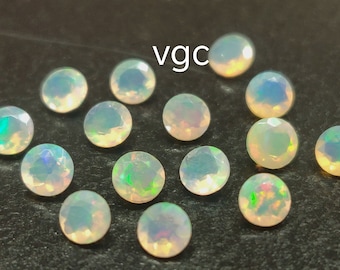 May include: A collection of 14 white opal gemstones, each with a slightly different iridescent sheen. The stones are round and have a smooth, polished finish.