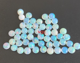 Può includere: Una collezione di 40 cabochon rotondi in opale iridescente. I cabochon hanno un diametro di circa 6 mm e un colore bianco latte con riflessi blu, verdi e rosa.