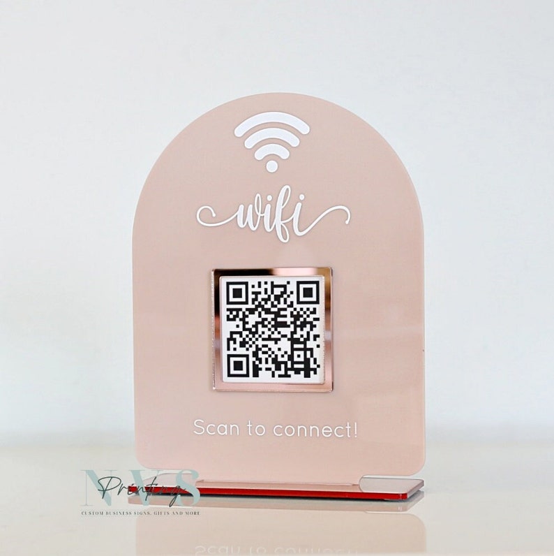 May include: A blush pink acrylic WiFi sign with a QR code for easy connection. The sign features the word "wifi" in a cursive font, a WiFi symbol, and the text "Scan to connect!"