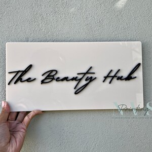 Custom Rectangle acrylic business sign in beige  colour, THE BEAUTY HUB in cursive font displayed on the middle in 3D gloss black acrylic