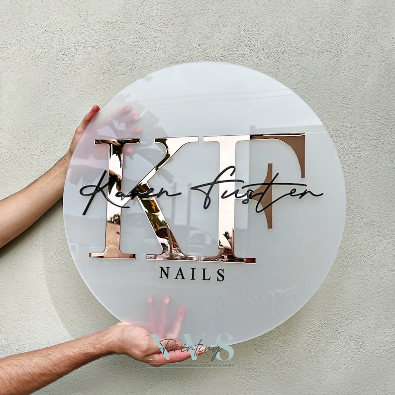 Round frosted acrylic business sign in  KF in the middle in serif font in rose gold mirror, Karen Fuster across the middle of KF in cursive font and 3D gloss black, NAILS on the bottom in 3D gloss black in serif font
