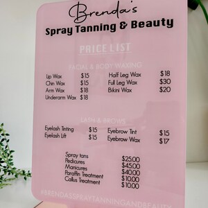 May include: A pink and black sign with the text "Brenda's Spray Tanning & Beauty" and a price list for various services, including waxing, lash and brow services, spray tans, pedicures, manicures, paraffin treatment, and callus treatment.
