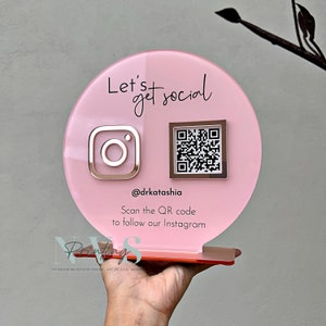 QR Code social media display stand in dusty pink acrylic backing, lets get social on top and instagram logo on the left in rose gold mirror acrylic and instagram QR code, instagram handle under the QR code and scan the QR code to follow our instagram